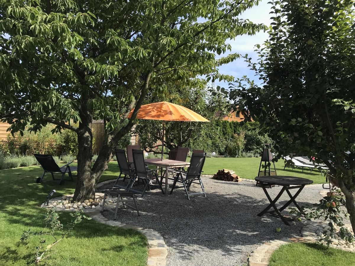 Garden with seating area under trees, table and chairs, orange parasol.