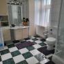 Bathroom with washing machine, shower, toilet and washbasin. Checkerboard tiles and white curtains.
