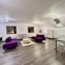 Modern loft with purple sofas, dining table and wooden floor.