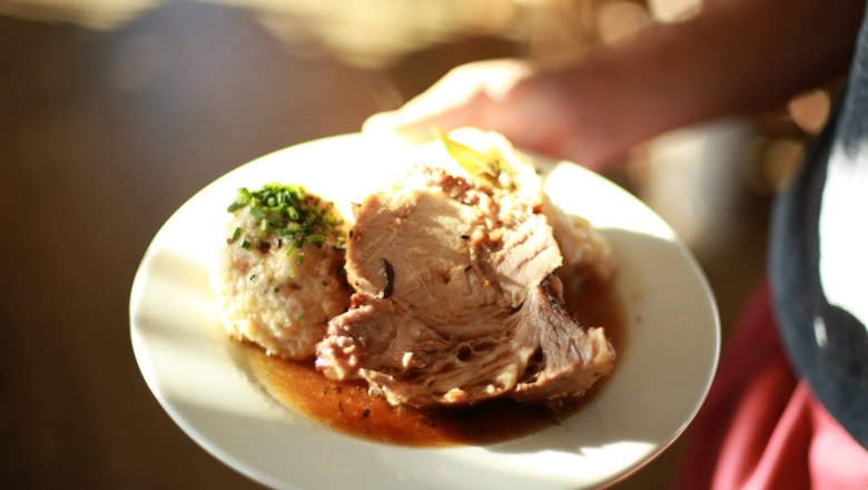 A plate with roast, dumplings and gravy.