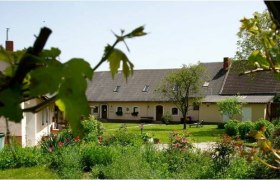 A rural house with a garden and trees in the foreground.