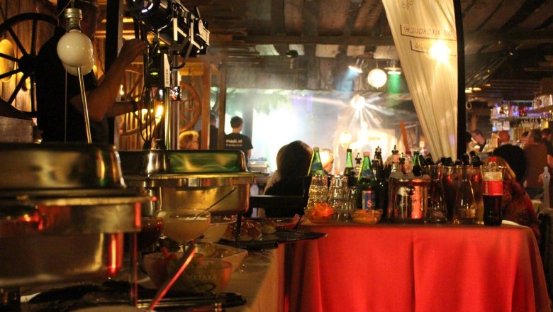 Buffet in the Preiner Stadl with drinks and food, illuminated by spotlights.