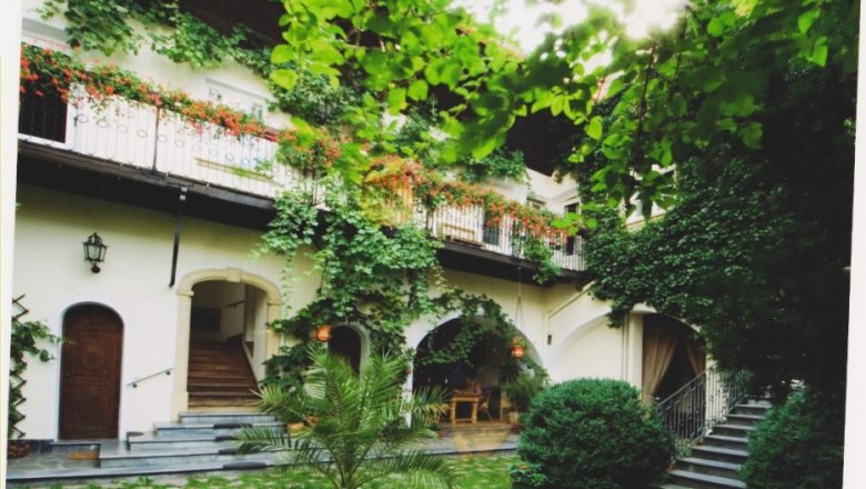 Melker Hof, © Roth A green inner courtyard with plants and a two-storey building with balconies.