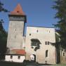 Ulmerfeld Castle with tower and entrance gate, surrounded by trees and flags.