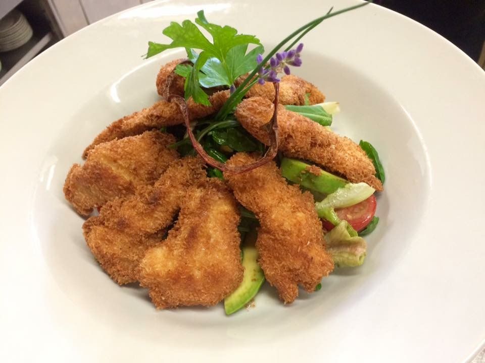 A plate with salad and baked goods, garnished with herbs.