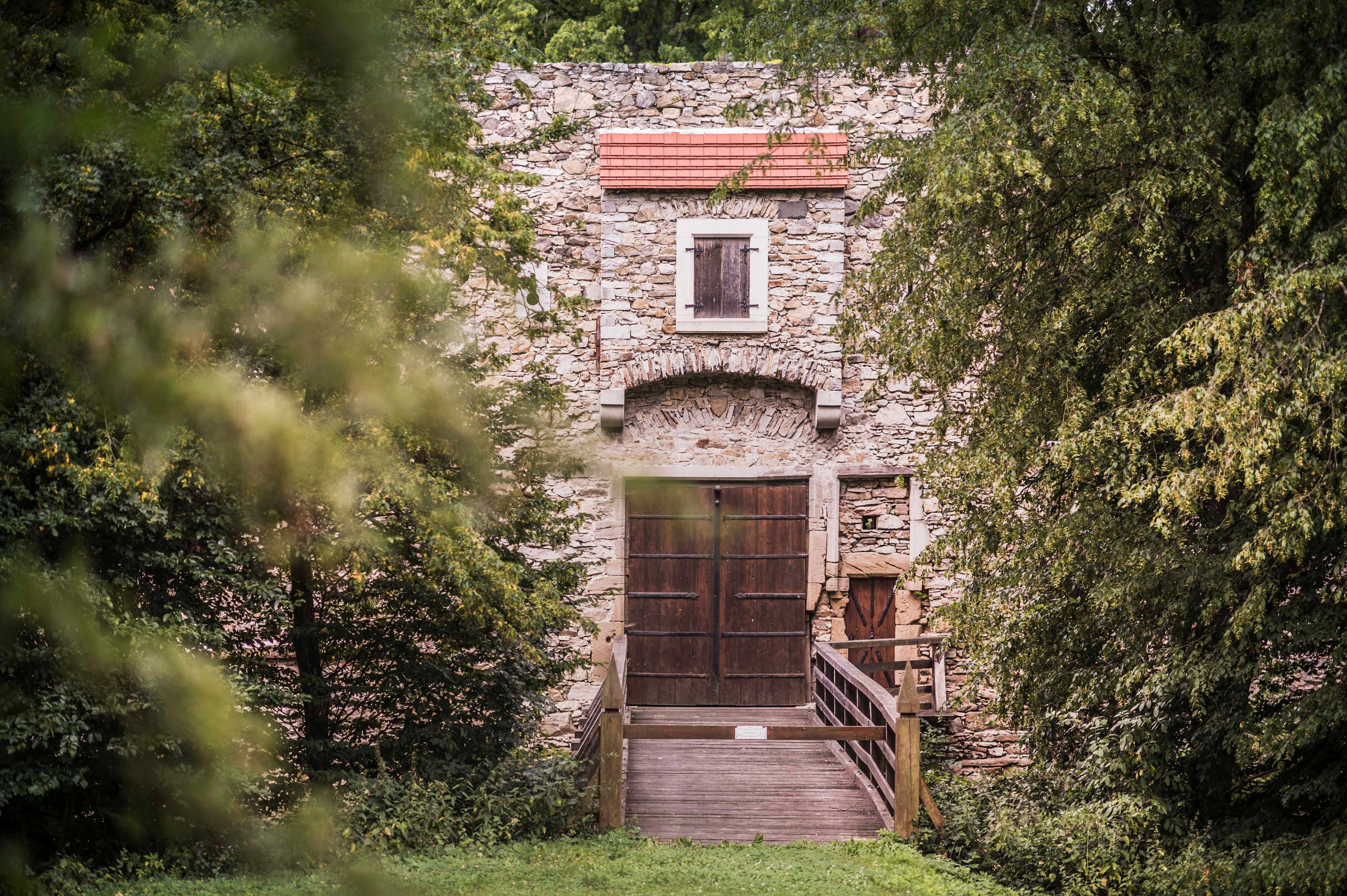 An old building with a wooden gate and a small wooden bridge in front of it.