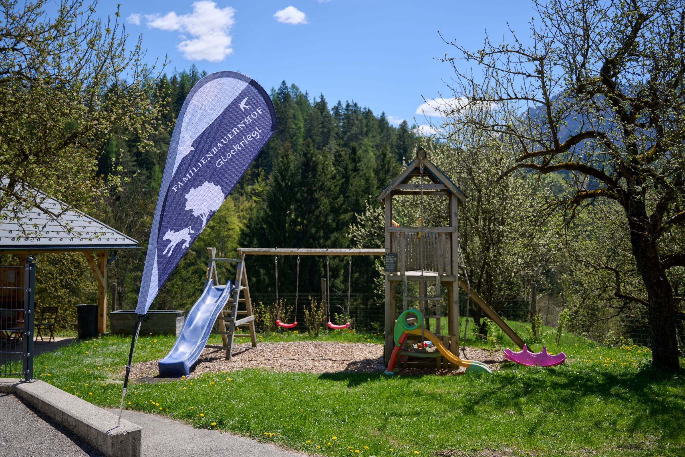 Playground with slide and swings, surrounded by trees and nature.