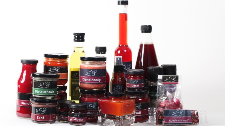 Various Dirndl Haus products, including honey, jelly, mustard and oil, on a white background.