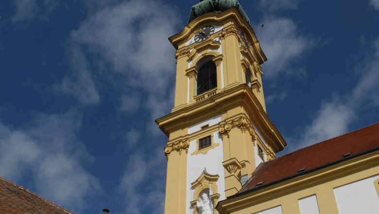 Yellow steeple of the Stockerau parish church against a blue sky.