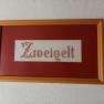 Embroidered picture with the word 'Zweigelt' in a wooden frame.