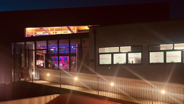 Night shot of the Schwechat brewery with illuminated windows and colored globe lights in the foreground.