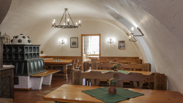 Interior view of a traditional wine tavern with wooden furniture and tiled stove.