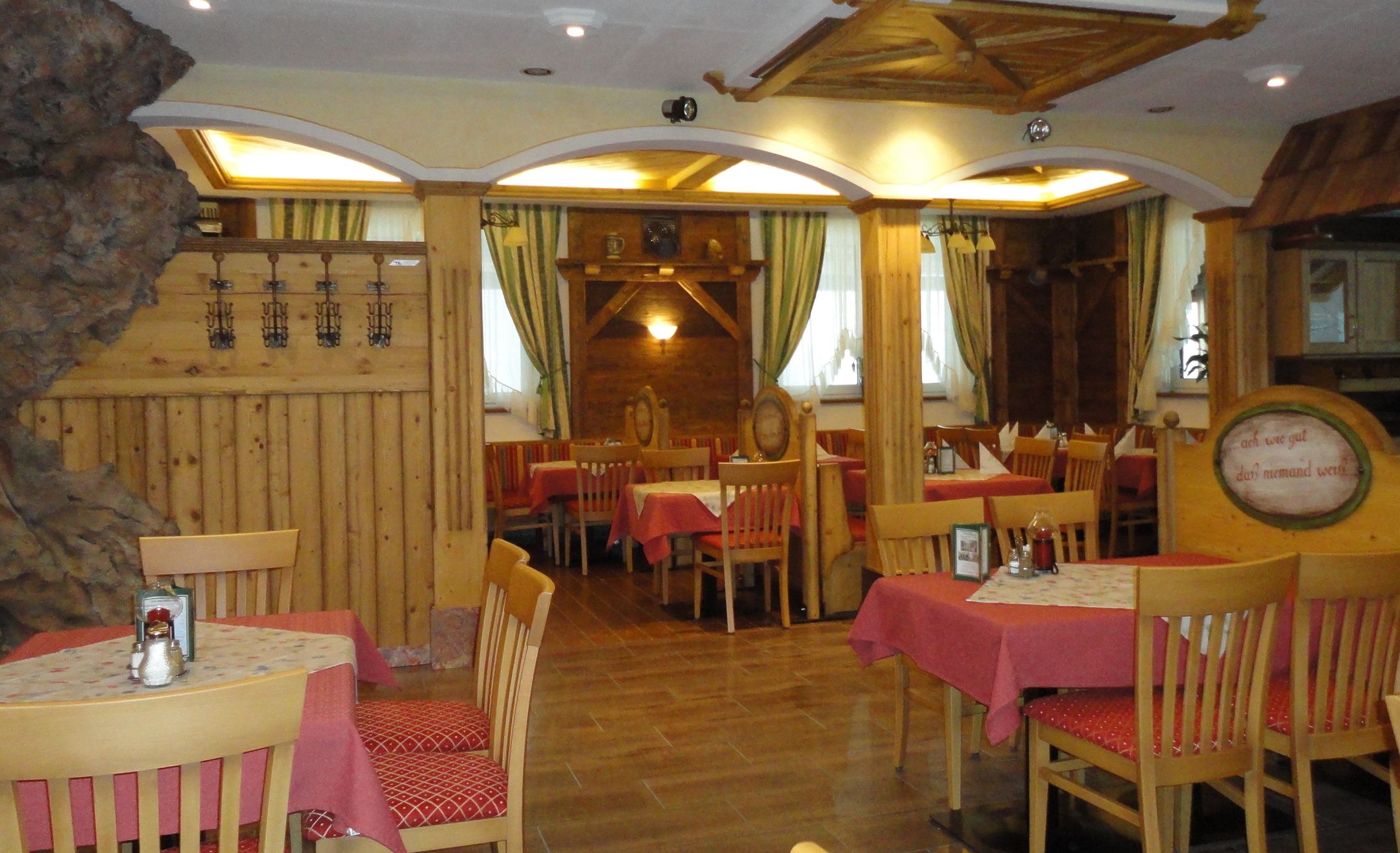 Cozy restaurant with wooden furniture and red tablecloths.
