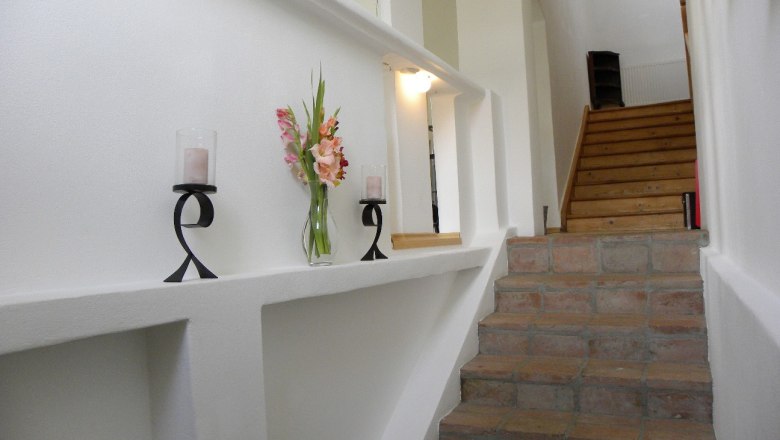 Interior view of a staircase with candlesticks and flowers on a ledge.