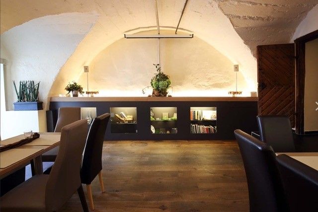 A stylish dining room with a vaulted ceiling, wooden floor and modern furniture. Plants and decorations adorn the walls.