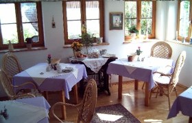 Cozy breakfast room with wicker chairs and purple tablecloths.