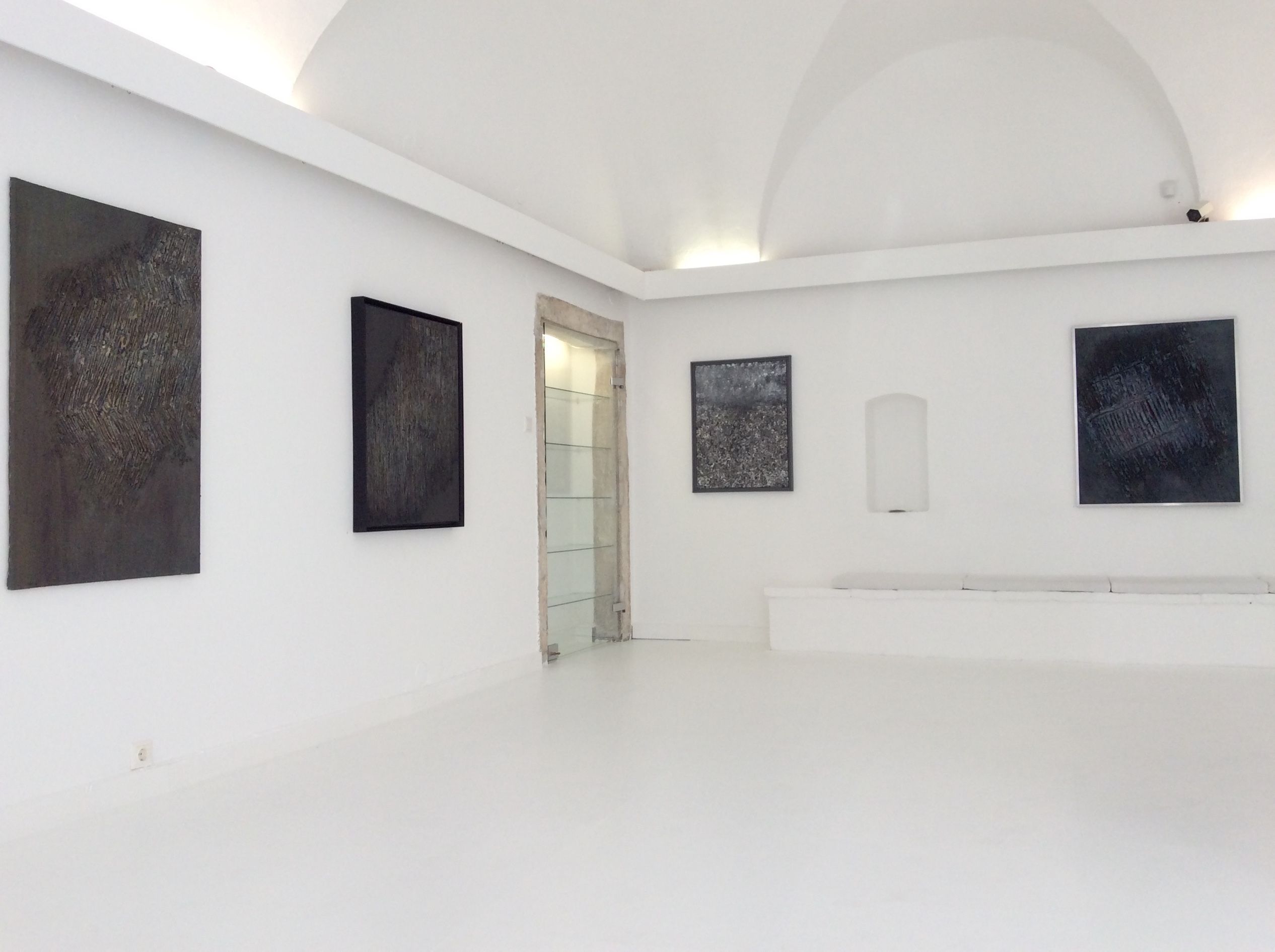 Interior view of a gallery with abstract paintings on white walls.