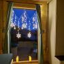 Window with curtains and snowflake fairy lights, two candles on the windowsill.