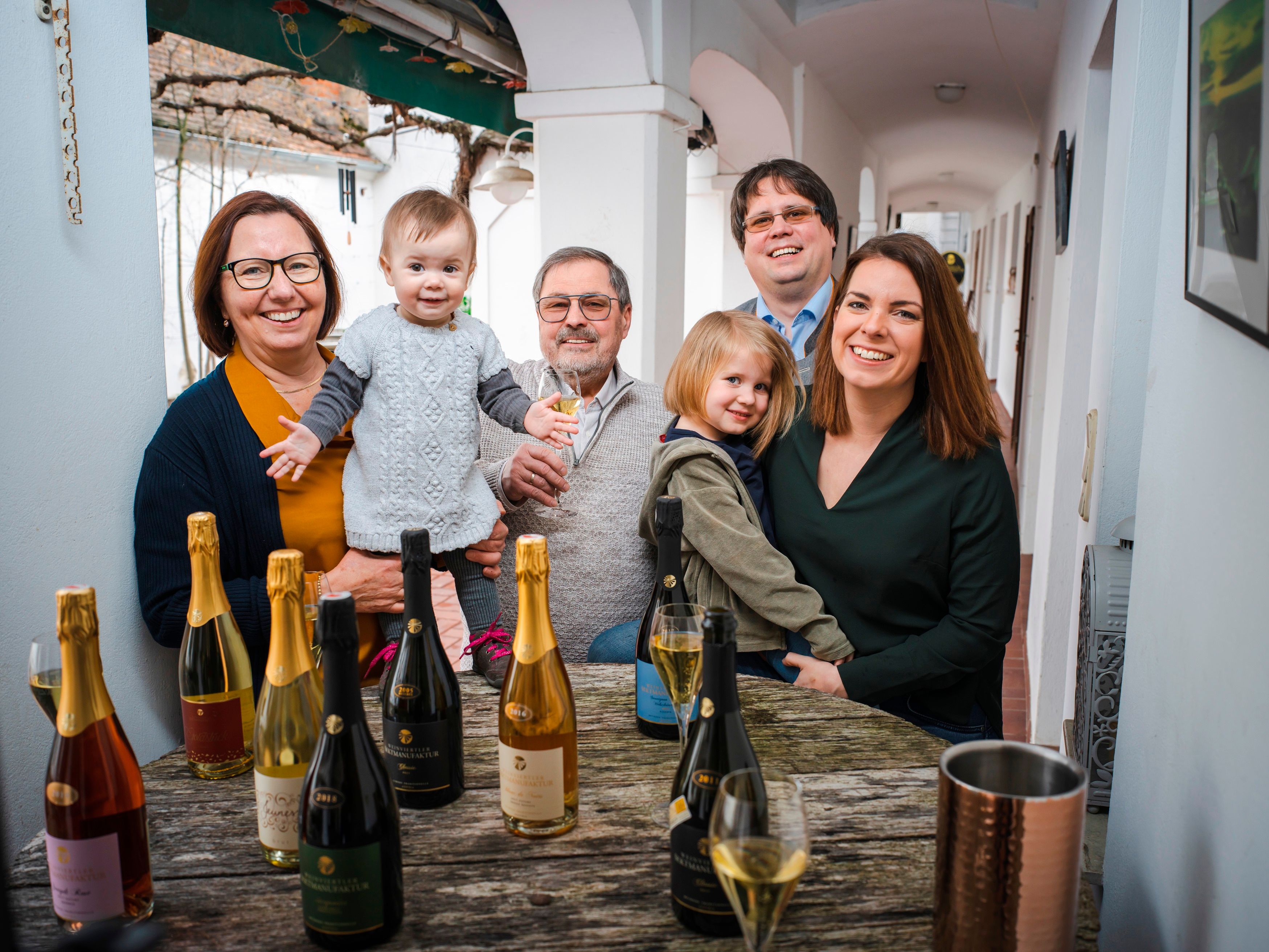 Family sitting at a table with champagne bottles and glasses.