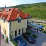 Exterior view of the Hotel Turmhof with red roofs and surrounding vineyards.