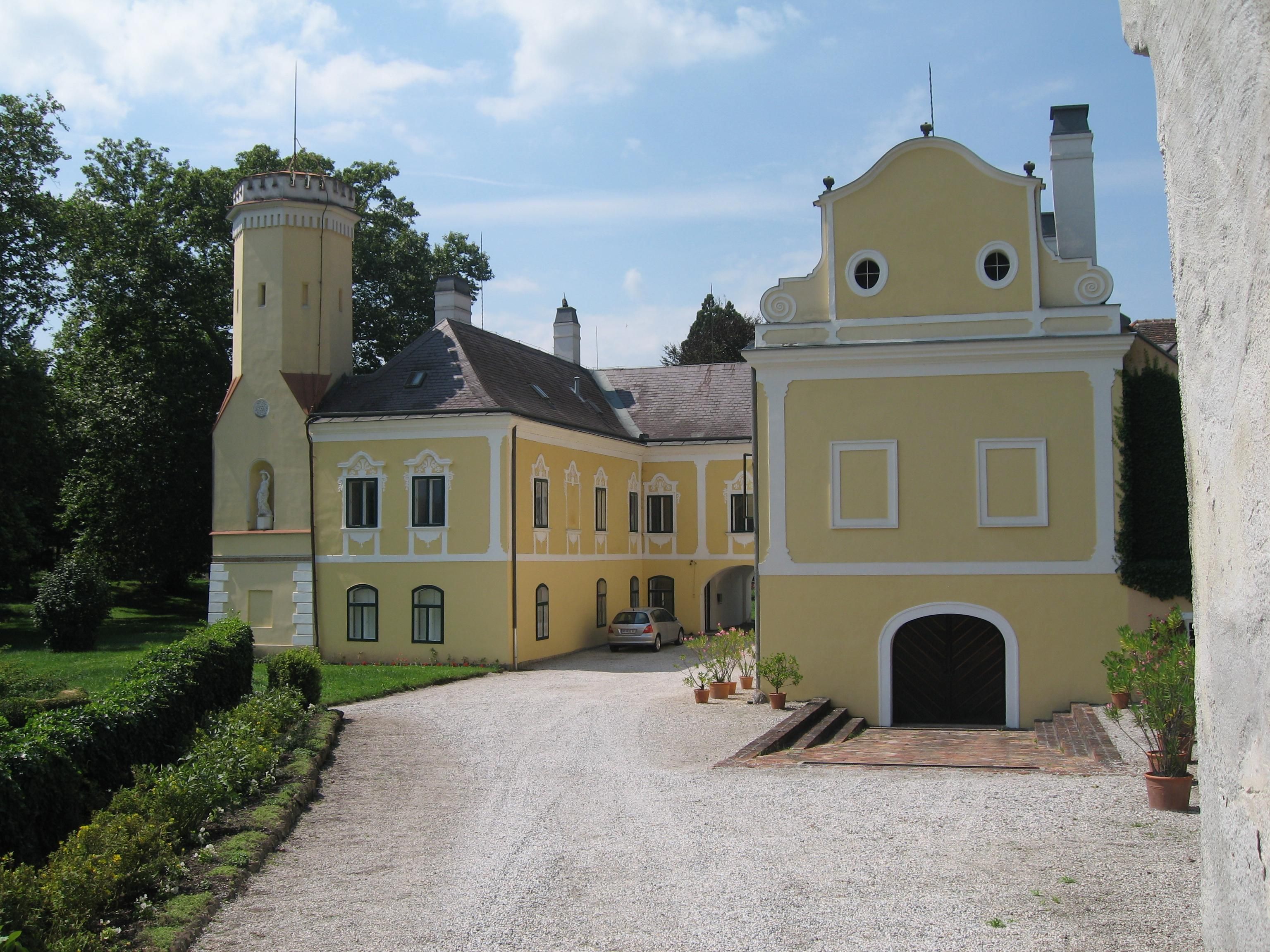 Yellow castle with tower and garden.