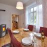 Dining room with wooden table, red chairs, set table and wood-burning stove.