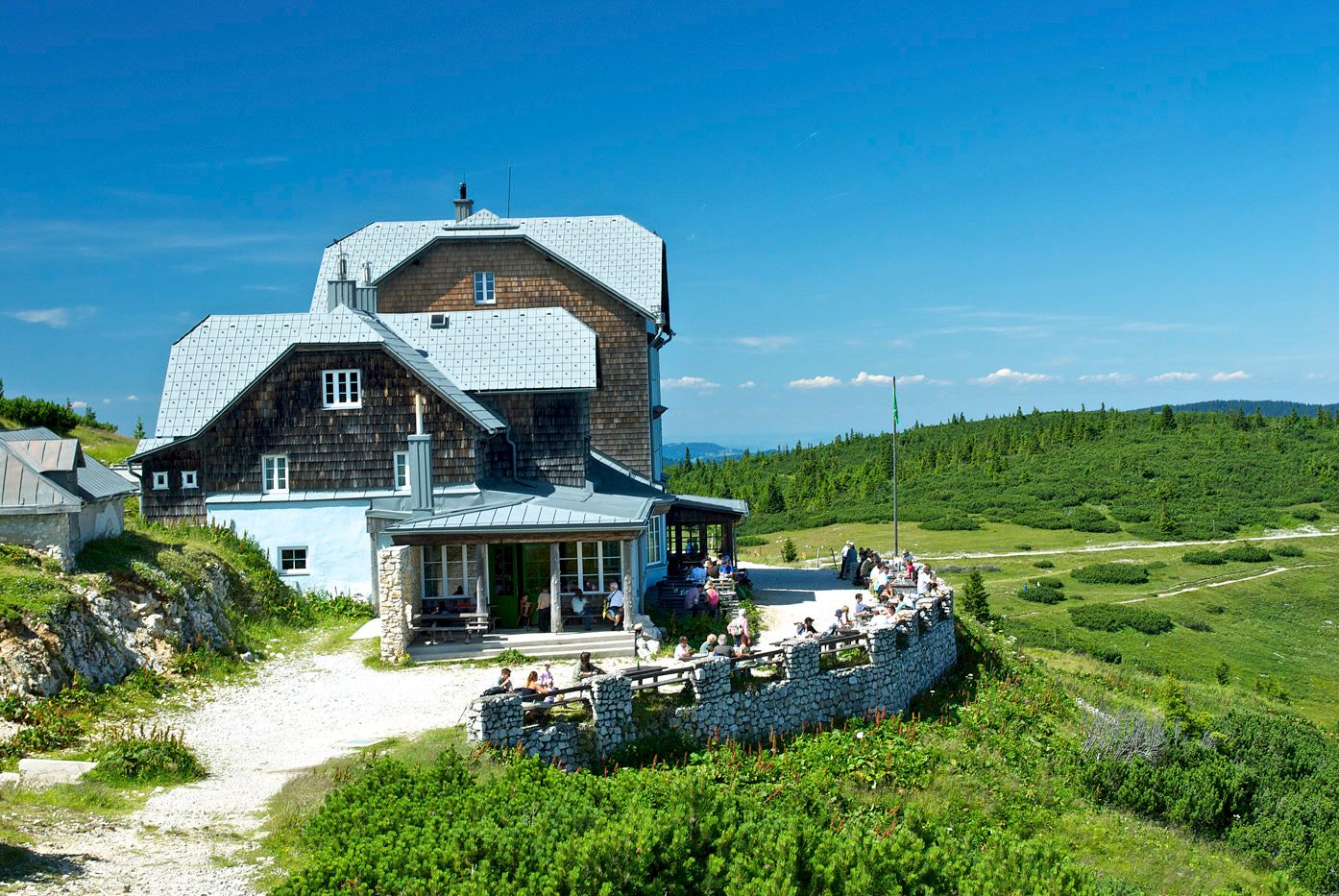 The Ottohaus on the Rax on a sunny day with blue skies and a green landscape.