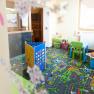 A colorful children's playroom with carpet, toys and small furniture.
