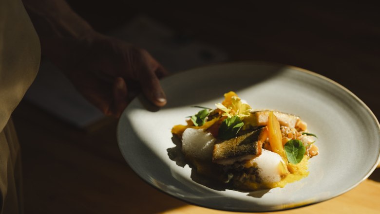 Gourmet dish with fish, risotto and pumpkin on a gray plate.