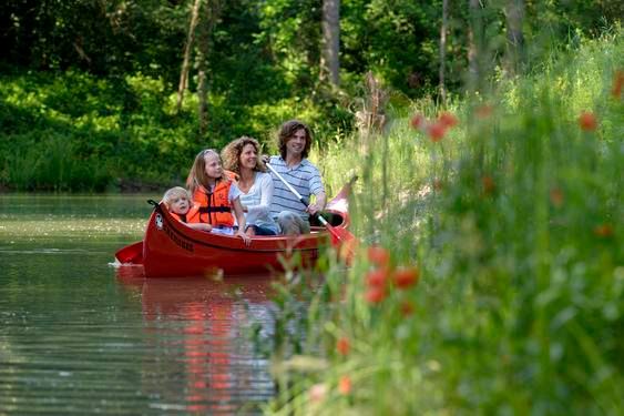 Family in a canoe on a river in the countryside.