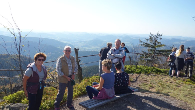 People enjoy the view from a mountain top with a wide view over the landscape.