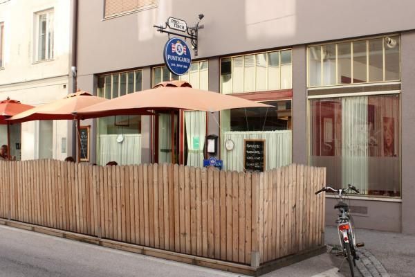 Exterior view of a café with wooden fence and parasols.