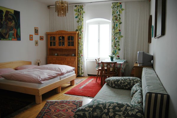 Cozy room with bed, sofa, table and wardrobe, decorated with carpets and curtains.