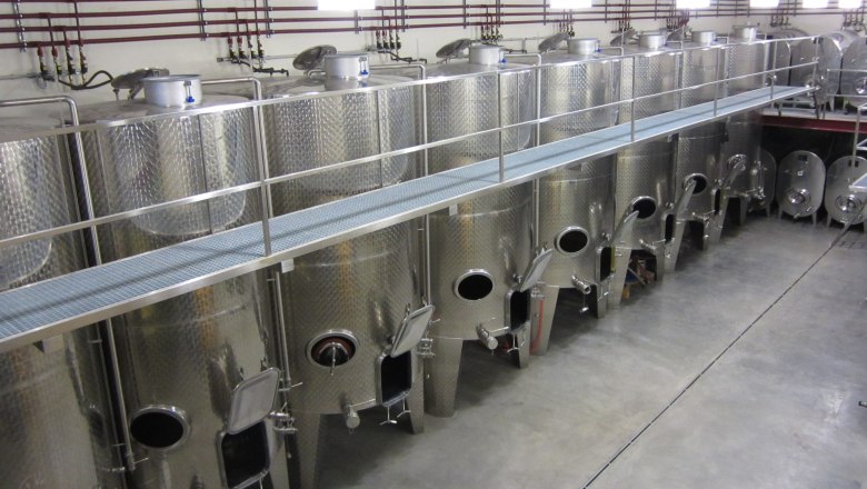Row of large stainless steel tanks in a modern winery.
