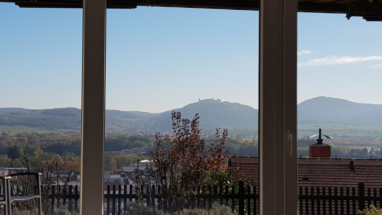 View from a window of a hilly landscape with a monastery on a hill in the background.