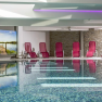 Indoor pool with red deckchairs, stone walls and a large mural.