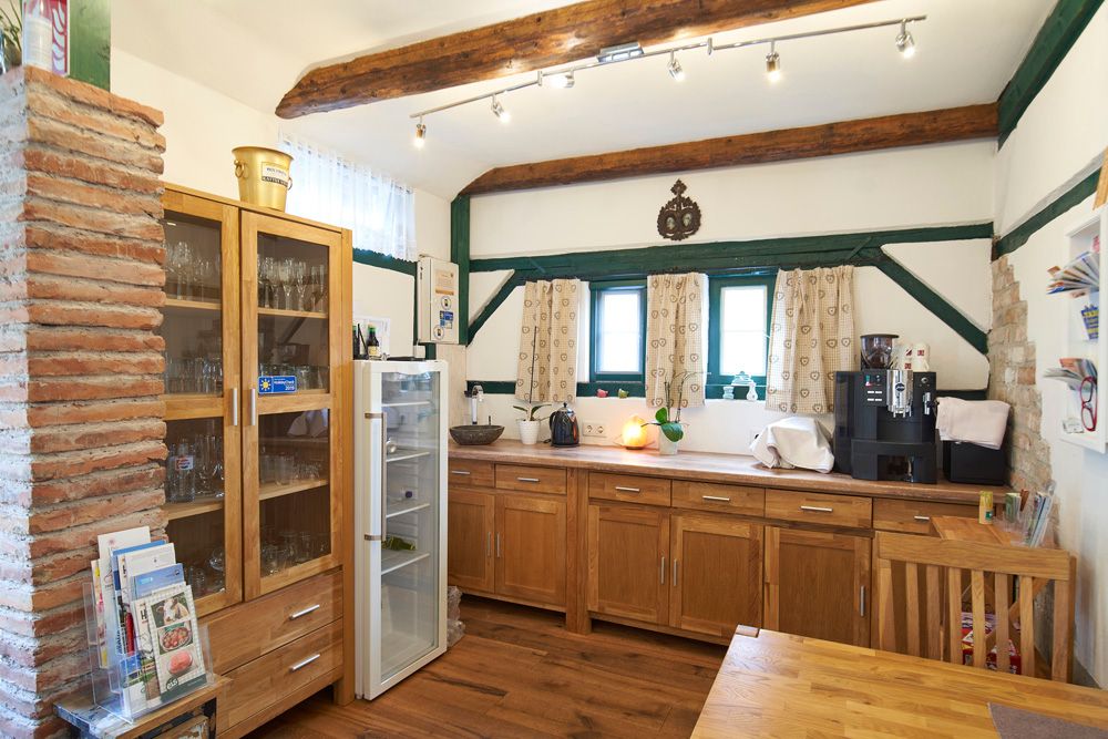 A cozy breakfast room with wooden furniture, a fridge, a coffee machine and decorative wooden beams on the ceiling.