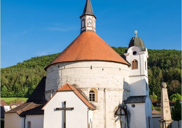 Scheiblingkirchen parish church with round tower and red roof against a blue sky.