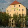Guest house by the bathing pond with reeds in the foreground.