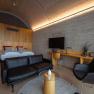 Modern hotel room with double bed, leather sofa, desk and TV.