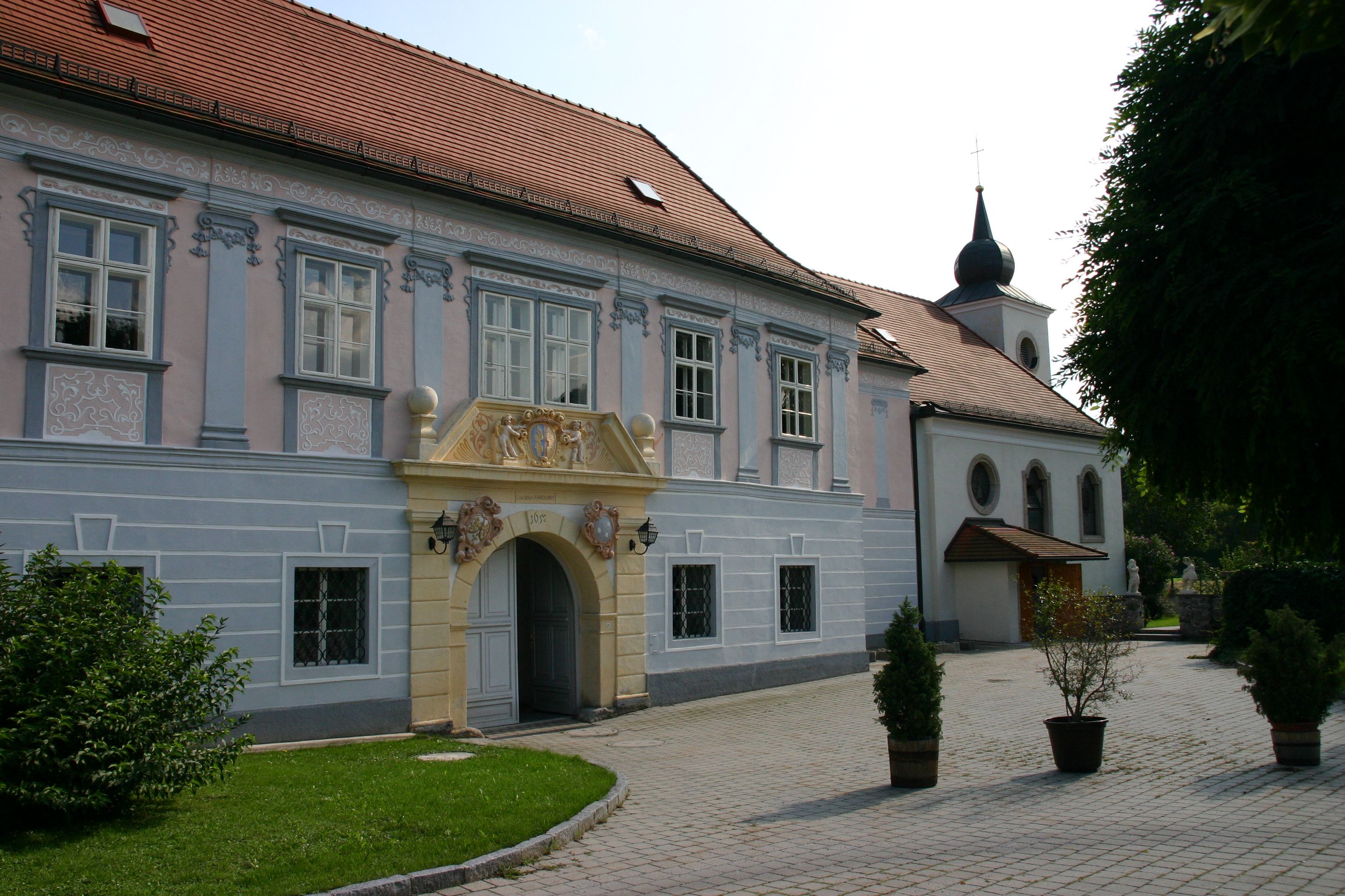 Historic building with ornate entrance and church in the background.