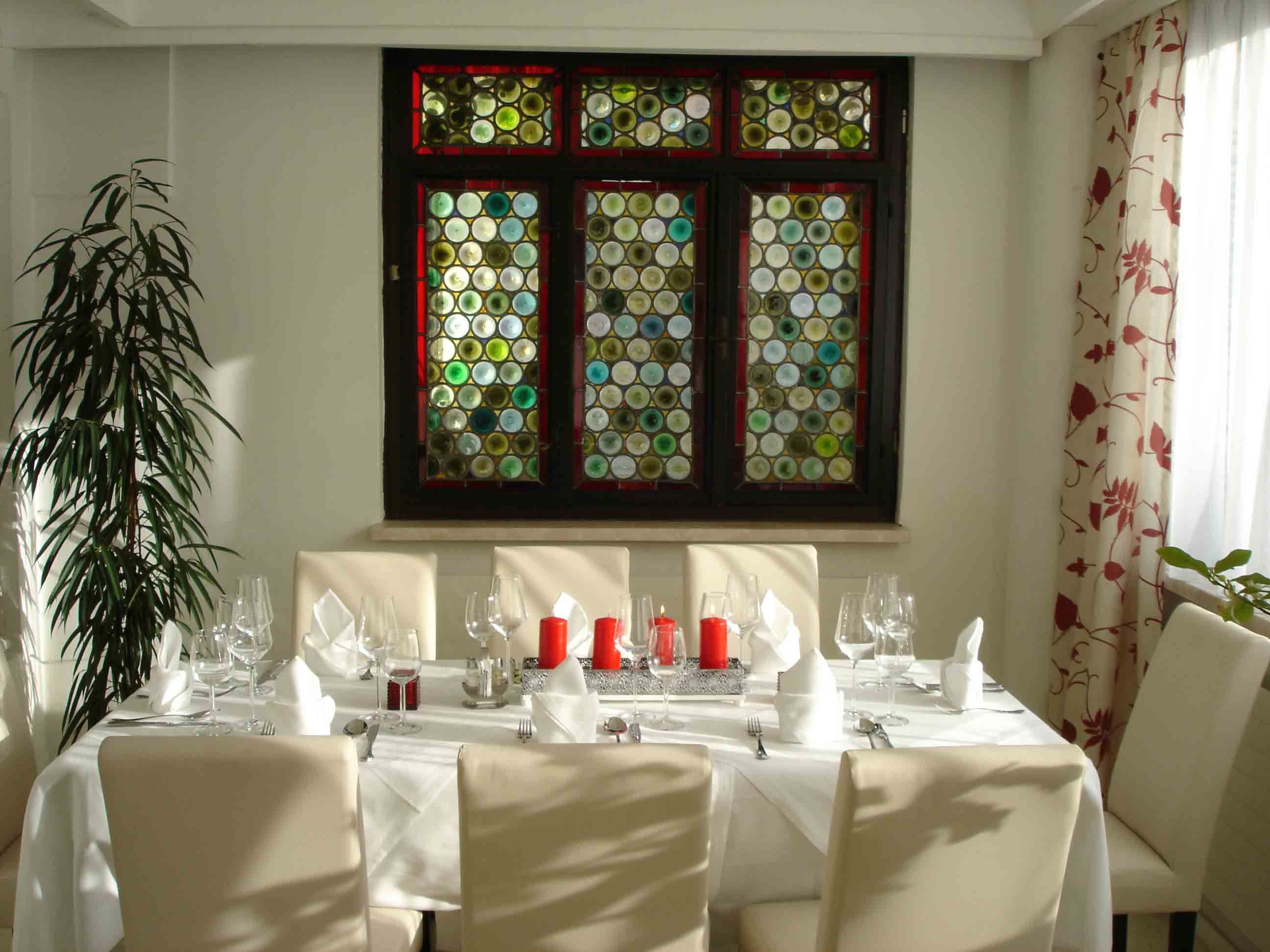 An elegantly laid table in front of a colorful glass window in a hotel.