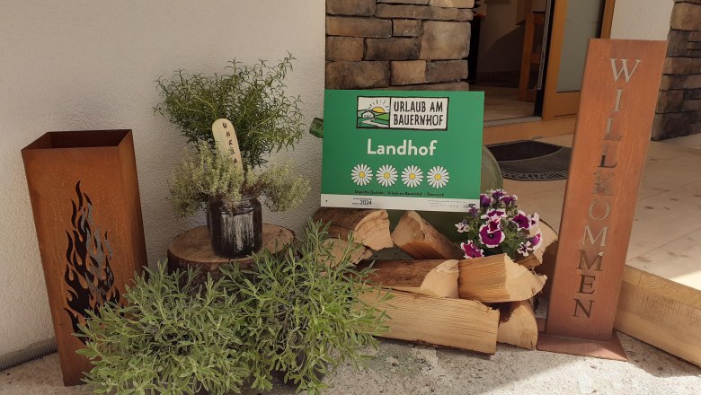 Entrance area with logs and a welcome sign.