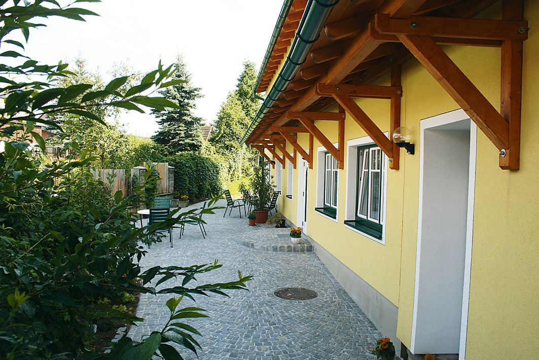 Paved courtyard with yellow building and garden furniture.