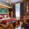 Cozy hotel room with wooden furniture, stone wall and large window.