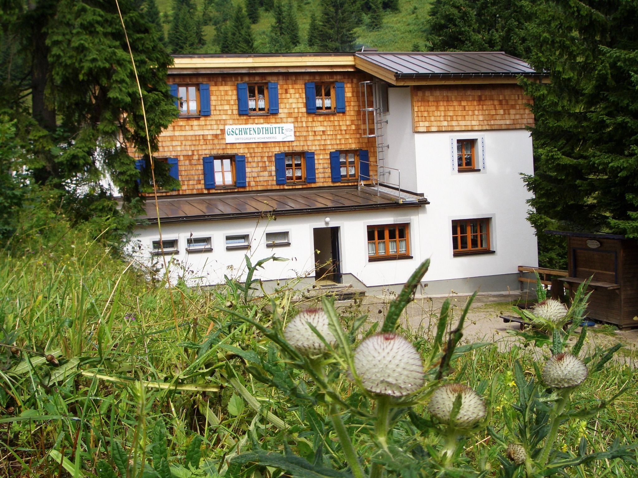 Gschwendthütte in Hohenberg, surrounded by green nature and trees.