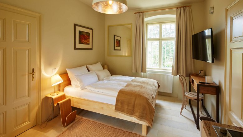 Comfortable bedroom with double bed, desk and large window.