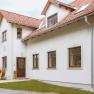 Exterior view of a house with red tiled roofs and white walls.