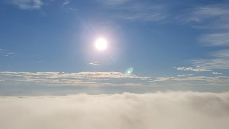 View from a viewing platform over a misty landscape with bright sunshine in a blue sky.
