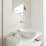 Modern bathroom with round washbasin and mirror.
